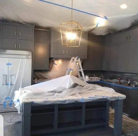 Kitchen masked in plastic and tape while cabinets are sprayed with new paint