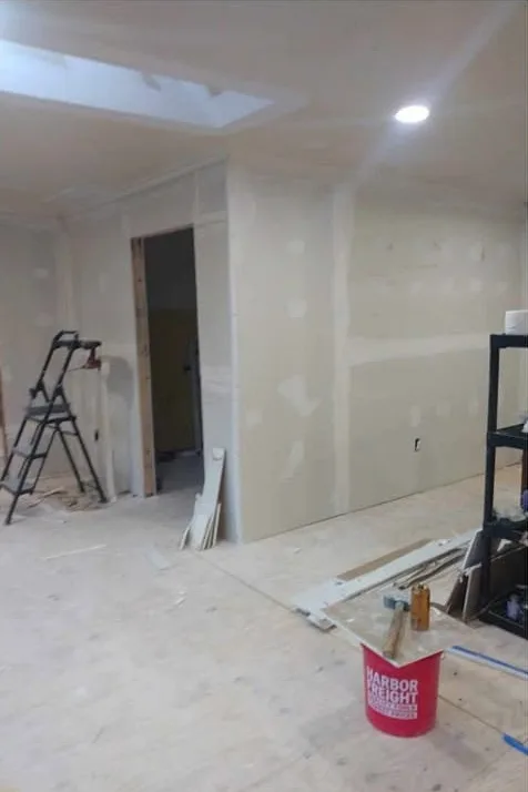 New drywall hung and taped in a living room with a skylight, ready for texture
